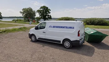 Maardu järve kalda kruusal nina vasakule pargitud katusemärgiga valge kaubik, kõrval roheline konteiner ja taga veepiir puudega, aastal 2025 sõitis kaubik Maardusse 22 drooniülevaatusele.